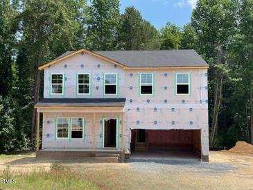 Two-story home with a two-car garage and a covered front porch, surrounded by lush trees at 62 Atherton Circle, Angier, NC 27501