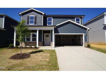 Charming two-story home featuring a spacious two-car garage, a welcoming front porch, and manicured lawn at 621 White Birch Ln, Angier, NC 27501
