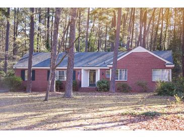 Charming one-story brick home featuring mature trees and a well-maintained lawn at 711 Evergreen Rd, Rocky Mount, NC 27803