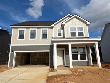 Two-story home featuring a two-car garage and inviting covered front porch, blending style and functionality at 766 Old Station Pointe, Angier, NC 27501
