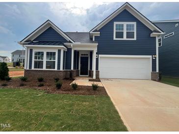Charming single-Gathering home showcases a two-car garage, dark blue siding and manicured front lawn at 771 Old Station Pointe, Angier, NC 27501
