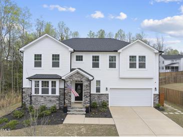 Charming two-story home boasts white siding, stone accents, well-manicured landscaping, and an attached two-car garage at 111 Kim Bark Path, Garner, NC 27529