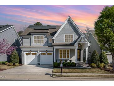 Charming two-story home featuring a two-car garage, gray siding, and manicured landscaping, solar panels, and a lovely sunset at 142 Old Piedmont Cir, Chapel Hill, NC 27516
