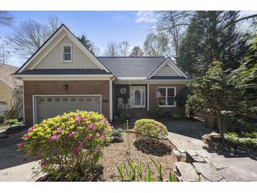 Charming brick home featuring a well-manicured lawn, an attached garage, and a cozy front porch at 155 Chimney Rise Dr, Cary, NC 27511
