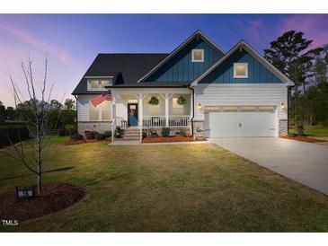 Charming two-story home with a welcoming front porch, attached garage, and manicured lawn at 16 Blue Monarch Ln, Fuquay Varina, NC 27526