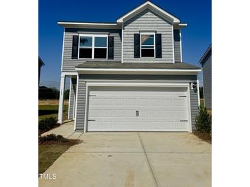 Two-story home with gray siding, black shutters, and a white garage door under a blue sky at 168 Bruce Dr, Dunn, NC 28334