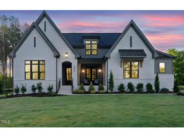 Charming exterior of a white painted brick home with gray accents and a well-manicured lawn at twilight at 2809 Theresa Eileen Way, Raleigh, NC 27603