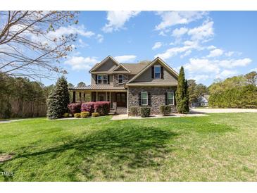 Charming two-story home with stone accents, manicured lawn, and lush landscaping at 3034 E Bay Court, Creedmoor, NC 27522