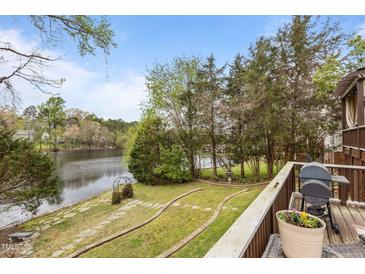 Beautiful backyard with a deck overlooking the lake, featuring well-maintained landscaping and a stone walkway at 6209 Remington Lake Dr, Raleigh, NC 27616