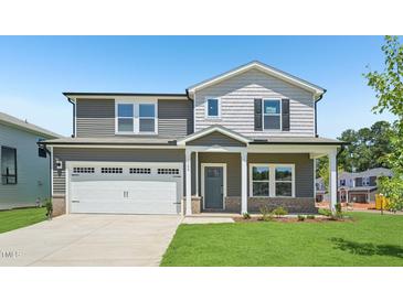 Charming two-story home boasts a landscaped yard, two car garage, and welcoming front porch at 700 Deschutes Dr, Garner, NC 27529