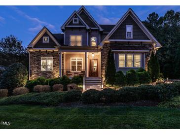 Charming two-story home with stone accents, manicured landscaping, and inviting front porch at dusk at 7312 Ridgeline Dr, Raleigh, NC 27613