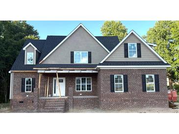 Traditional brick home featuring black shutters, a covered porch, and architectural roof elements at 801 Emmett Ct, Spring Hope, NC 27882