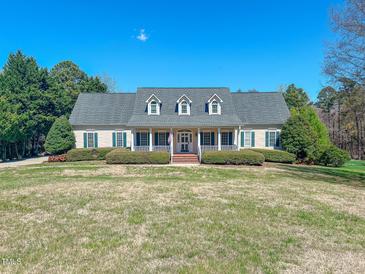 Charming home featuring a welcoming front porch, well-manicured lawn, and lush landscaping at 98 Lochridge Dr, Roxboro, NC 27573