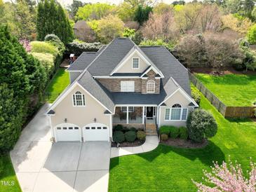 Beautiful two-story home featuring a stone facade, a covered porch, a well-manicured lawn, and a three-car garage at 213 Billingrath Turn Ln, Cary, NC 27519