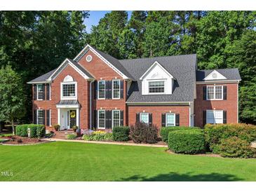 Stately brick home featuring a manicured lawn, mature trees, and a welcoming front entrance with tasteful landscaping at 2514 Mcgowan Ct, Wake Forest, NC 27587