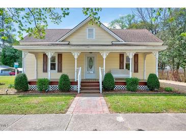 Charming home featuring a welcoming front porch, complemented by neat landscaping and a brick walkway at 309 W Parrish Dr, Benson, NC 27504