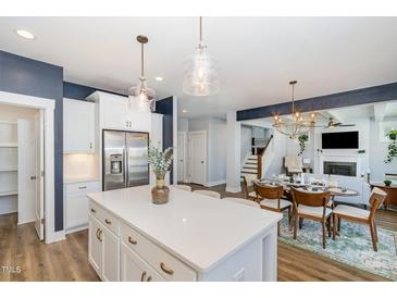 Open concept kitchen features a large island, stainless steel appliances, and views to the dining and living area at 332 Tumbling River Dr, Wendell, NC 27591