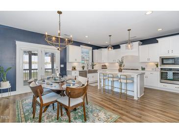 Beautiful kitchen with white cabinetry, an island with barstool seating, stainless appliances, and a dining area at 332 Tumbling River Dr, Wendell, NC 27591