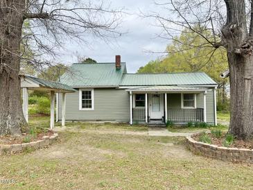 Charming single-story home with a green metal roof and covered porch, surrounded by mature trees at 540 S Cheatham St, Franklinton, NC 27525