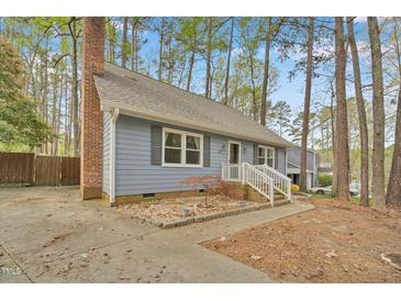 Charming blue home with a brick chimney and a landscaped front yard surrounded by mature trees at 1010 Flanders St, Garner, NC 27529