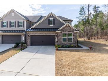 Charming townhome with stone and gray shingle exterior, a two-car garage, and manicured landscaping at 1012 Catch Fly Ln, Durham, NC 27713