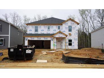 Unfinished two-story home exterior featuring a garage and covered entry with construction materials at 2130 Cherry Creek Rd, Haw River, NC 27258