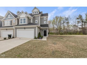 Charming gray townhome boasts an attached garage, manicured lawn, and inviting entryway, blending comfort and style at 248 Shingle Oak Rd, Wake Forest, NC 27587
