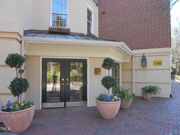 Inviting entryway with double glass doors, potted plants, and a well-maintained brick pathway at 2801 Glenwood Gardens Ln # 106, Raleigh, NC 27608