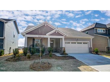Charming single-Gathering home featuring a two-car garage, covered porch, and a well-maintained front yard at 296 Providence Creek Dr, Fuquay Varina, NC 27526