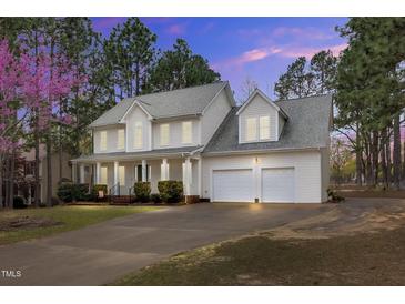 Charming two-story home with a two-car garage and well-manicured landscaping at dusk at 384 Rocky Run Ln, Lillington, NC 27546