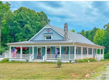 Charming home featuring a full wraparound porch, a stone chimney, and beautiful mature landscaping at 468 Loftis Loop Rd, Roxboro, NC 27574