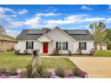 Charming single-story home with a bright red front door, solar panels and well-maintained landscaping at 503 N Sellers St, Selma, NC 27576