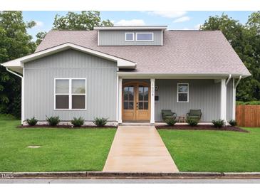 Charming home with a well-maintained front yard, covered porch, and natural wood front door at 1008 North St, Durham, NC 27701