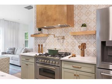 Gourmet kitchen featuring stainless steel appliances, custom backsplash, and a modern range at 1008 North St, Durham, NC 27701
