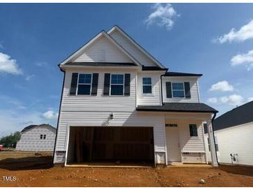 Two-story home featuring white siding, black trim, an attached garage, and a well-manicured lawn at 118 Fairwinds Drive Dr, Lillington, NC 27546