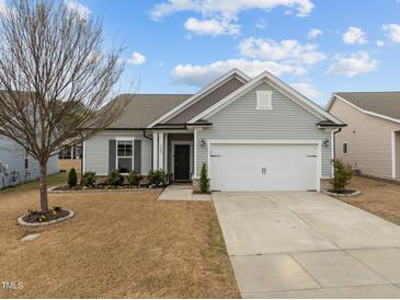 Charming single-story home featuring a two-car garage, landscaped yard, and light gray vinyl siding at 1207 Bluewater Way, Durham, NC 27703