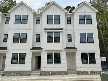 Modern townhome complex featuring white siding, black window trim, and symmetrical design elements at 1543 Crescent Townes Way, Raleigh, NC 27604