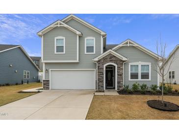 Charming two-story home with gray siding, stone accents, and a two-car garage at 235 Mallard Loop Dr, Clayton, NC 27527