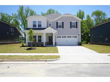 Charming two-story home featuring a two-car garage, manicured lawn, and inviting covered entry at 3849 Rosebush Dr, Zebulon, NC 27597