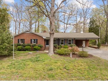 Charming brick home featuring mature trees, covered parking, and lush landscaping at 5130 Guess Rd, Durham, NC 27712