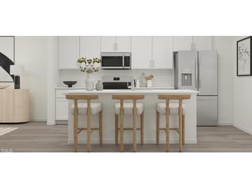 Modern kitchen features white cabinets, stainless steel appliances, and a kitchen island with seating at 804 Basswood Glen Trl, Knightdale, NC 27545