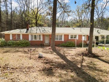 Charming single-story brick house featuring a covered carport and mature trees in a spacious front yard at 906 Perry Rd, Zebulon, NC 27597