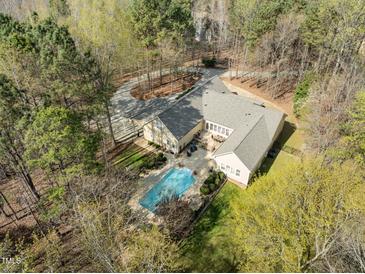 Stunning aerial view of a large home with a private pool and landscaped grounds surrounded by trees at 120 Teasel Ct, Clayton, NC 27527