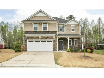 Charming two-story home with a stone and wood facade, well-manicured lawn, and attached two-car garage at 127 S Harrison Place Ln, Fuquay Varina, NC 27526
