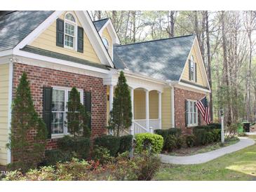 Charming home with brick and siding, lush landscaping, and an inviting walkway at 1309 Wakefield Farm Rd, Zebulon, NC 27597