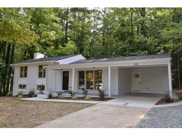 A charming single-Gathering home featuring a white exterior, a covered carport, and a well-manicured lawn with mature trees at 245 Marilyn Cir, Cary, NC 27513