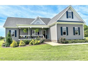 Charming gray home featuring a welcoming front porch, landscaped yard, and stylish architectural details at 2540 Levi Ln, Bahama, NC 27503