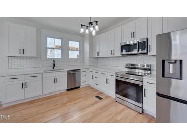 Bright kitchen features white cabinets, stainless steel appliances, white subway tile backsplash and hardwood floors at 301 E Umstead St, Durham, NC 27707
