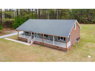 Charming single-story home featuring a welcoming porch, neutral siding and brick accents, set in a wooded area at 3026 Shoeheel Rd, Kenly, NC 27542