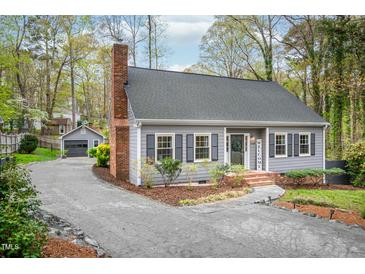 Charming home with a brick chimney, welcome decor, meticulous landscaping, and a detached garage at 5608 Ventura Dr, Durham, NC 27712